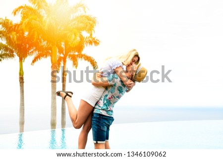 A couple on the terrace of prestigious hotel, with palm on the background and sunset