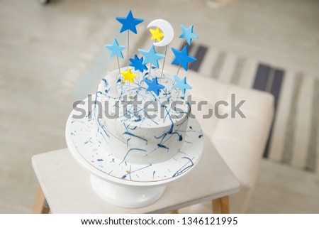 Birthday navy blue and silver decorations with cake, toys, garlands and figure for little baby party on a white bricks background.