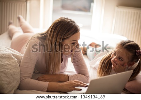 Mom, cartoon is great. Mother daughter using laptop.