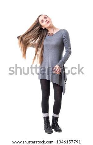 Relaxed young pensive woman looking up daydreaming while brushing her long hair. Full body isolated on white background. 