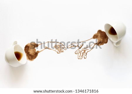 Two espresso cups with hand drawing hand to hand. Helping hands, coffee art or creative concept. Adam creation. Top view
