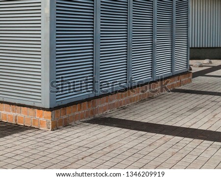 Metal industrial construction. Fixed metal louvers. Pavement on the ground.