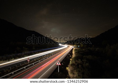 Highway road with lights of cars on long exposure and stars of night