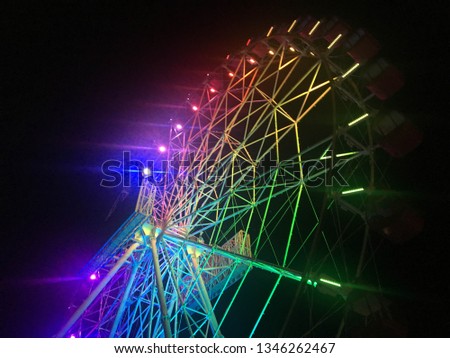 Ferris wheel at night with colorful neon light in Jakarta, Indonesia with dark sky background.
