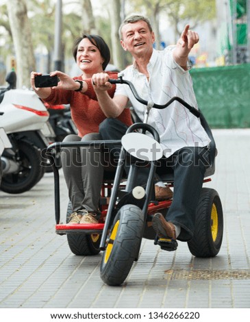 Pleasant couple with double bike and camera in vacation on city street