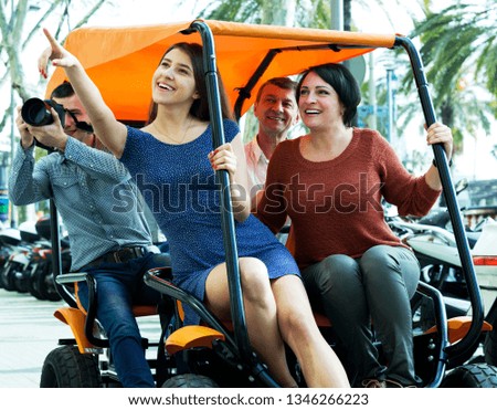 Beautiful couple with adult children sitting in grand tour electric and taking pictures of Europenian city
