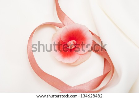 begonia flowers decorated with ribbon on silk background