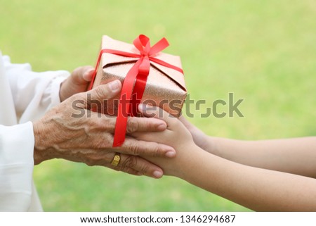 Cropped image of the girl giving a gift to a grandmother on birthday