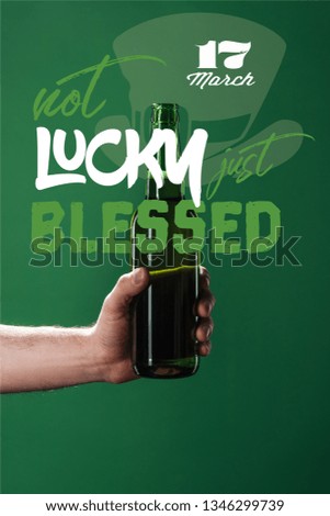cropped view of man holding beer bottle near not lucky just blessed lettering on green background