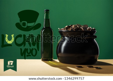 beer bottle and black pot with golden coins near lucky you lettering on green background