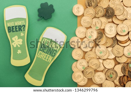 top view of golden coins with dollar signs, shamrock and paper beer glasses with lettering on green background 