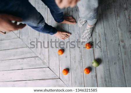 The legs of the girl and the guy on the floor. Scattered oranges and apples