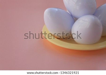 White eggs on a yellow plate on the background in pink pastel color. Small plastic toy eggs. Kids toys. Minimalism food concept. Easter concept. 