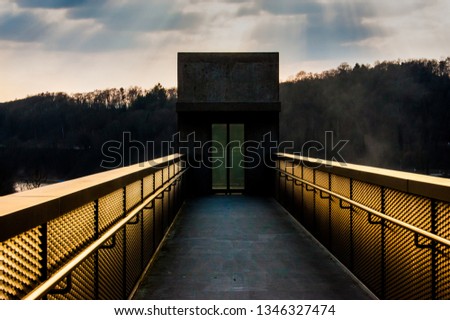 Walkway with golden screen sides going to tower with closed green door