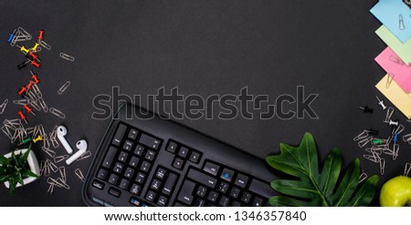 Flat lay, top view office table desk. Workspace with blank clip board, keyboard, office supplies, pencil, green leaf, and headphone on black background. office products and stationery framed. Notebook