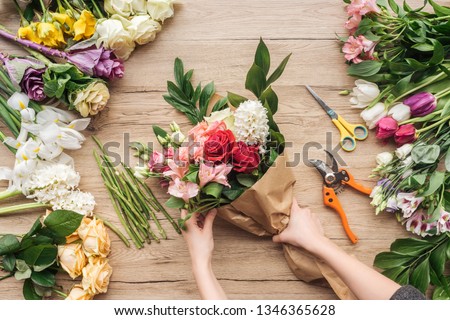 Cropped view of florist making flower bouquet on wooden surface Royalty-Free Stock Photo #1346365628