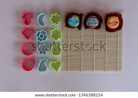 Bakery and cookie mold., Fancy donuts on bamboo sushi rolling mat., On a light pink background.