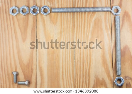 assorted nuts and bolts square frame on wood texture background. free area