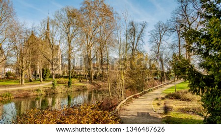 Beautiful view of a river between trees and trails in the Proosdij park with a church in the background, wonderful and sunny winter day in Meerssen south Limburg in the Netherlands Holland