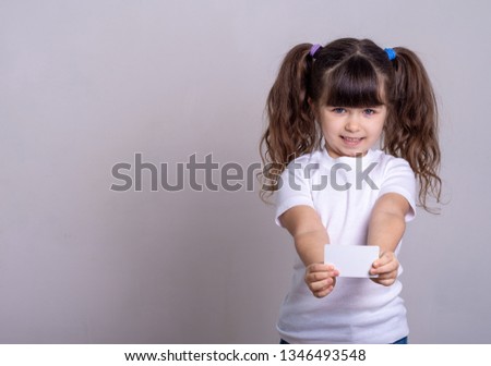 Girl with happy expression holding a bank card. Customer and  buying. Copy space, grey background.  