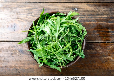 fresh arugula salad in a clay plate on the table. space for text Royalty-Free Stock Photo #1346527100