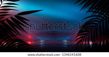 Dark street with neon lights and spotlights. Abstract rays and lines of light in the dark. Light pyramid, a triangle in the center. Reflection in the wet pavement of city lights.  tropical leaves.