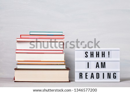 Heap of books and light box with the text I am reading