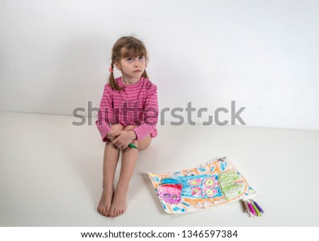 Little girl with pigtails paints a picture of felt-tip pens on a white background.