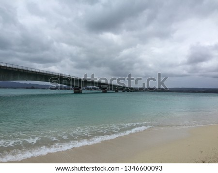 A picture of Okinawa on a cloudy day, the waves and the bridge.