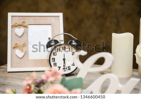 closeup photo of a wedding decor: a vintage wooden table with a flower arrangement, photo frame, candles, lamps, white inscription love on it
