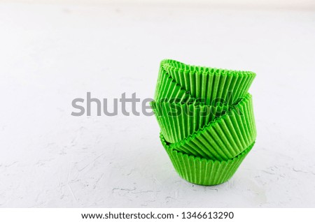 Brightly green colored paper baking cups for cupcakes or muffins on light grey conkrete background, copy space