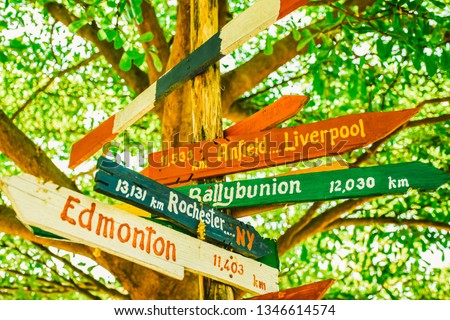 Handmade wooden sign on the tree with names of cities and distance to Anfield Liverpool, Ballybunion, Rochester, Edmonton, Folkestone, Kirkcaldy at Chiang Mai hostel in Thailand for backpackers.