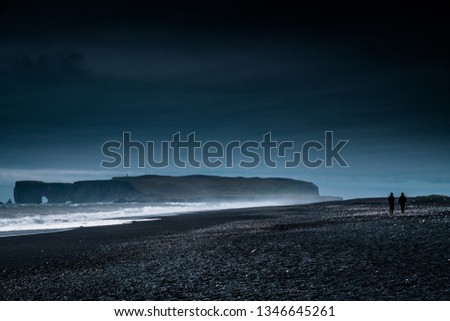 Black Sand Beach, Iceland dark night during sunrise with couple walking