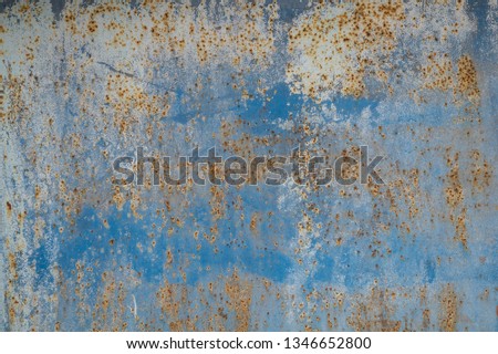Grunge background  - rusty light blue metal surface. An old metal wall painted with multi-layered light blue paint that shows a lot of dark spots and rust stains on the paint.