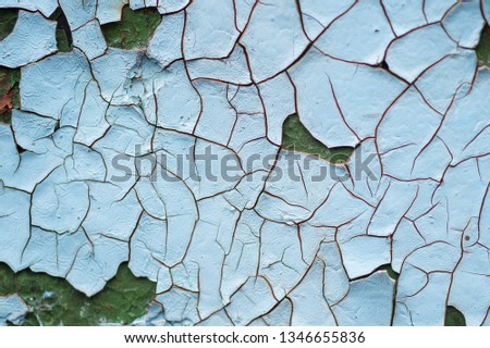 Blue background texture of an old cracked paint. Textured surface with a multi-layered and multi-colored paint that cracks and peels. Light blue background texture. Cracks in the paint. 