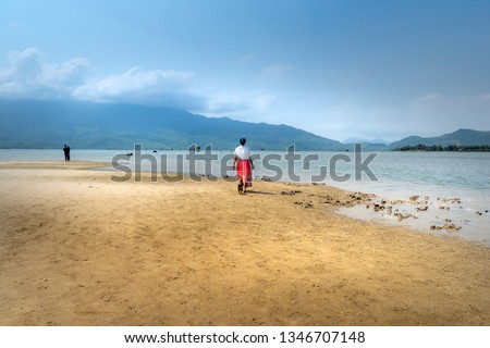 Female tourist walk relaxing on the sand at Lap An lagoon, Lang Co Bay. Lang Co Bay is one of the most famous and beautiful bays of the world at Thua Thien Hue province, Vietnam