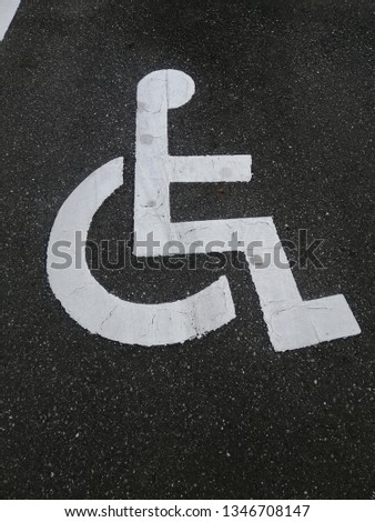 Handicapped sign on the asphalt road in car park. 