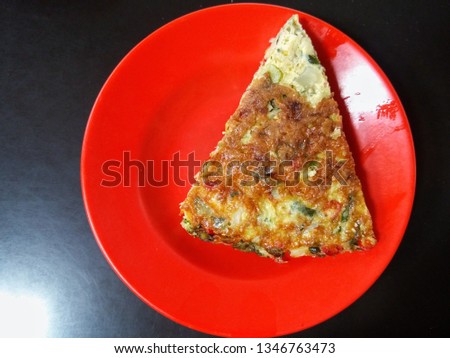 A piece of omelet on an orange plastic plate
