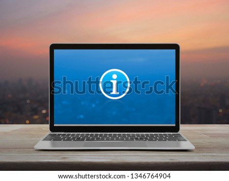 Information sign icon with modern laptop computer on wooden table over blur of cityscape on warm light sundown, Business customer support online concept