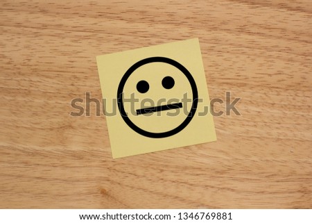 a yellow piece of paper with a face on a wooden board