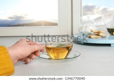 Woman with cup of hot winter drink near window, closeup