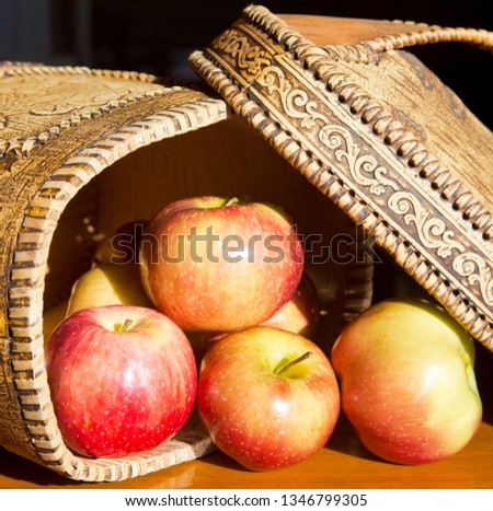 Ripe red-yellow apples spilling out of the birch bark box