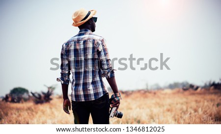 African man photographer holding camera on a dry field.16:9 style