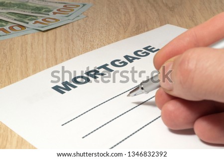 Empty form to fill mortgage with money, hand and pen on the table close-up.