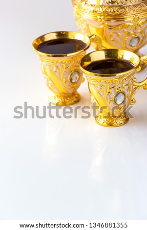 Still life with traditional golden arabic coffee set with dallah and cup. White background. Ramadan concept.