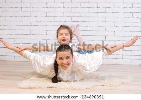 5 year old daughter riding on her mother portrayed flying against the wall