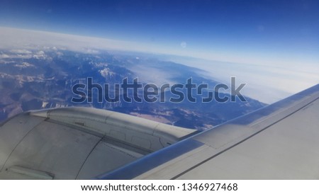 flying and traveling abroad, bird eye view from airplane window on the jet wing on cloudy blue sky iceberg mountain aboard morning winter time, journey backgrounds