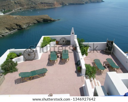 Sun loungers on a Greek resort terrace with sea view.