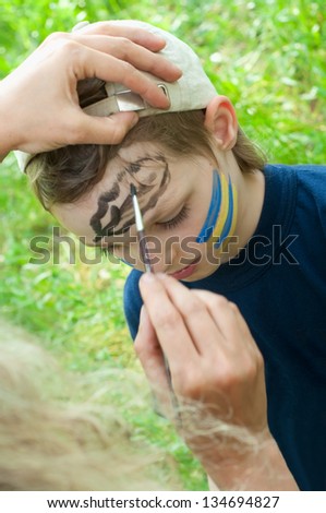 outdoor portrait of a child with his face being painted