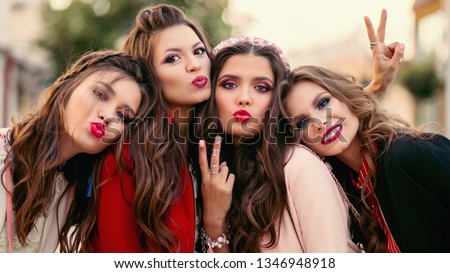 Group of gorgeous girlfriends smiling and gesturing at camera.